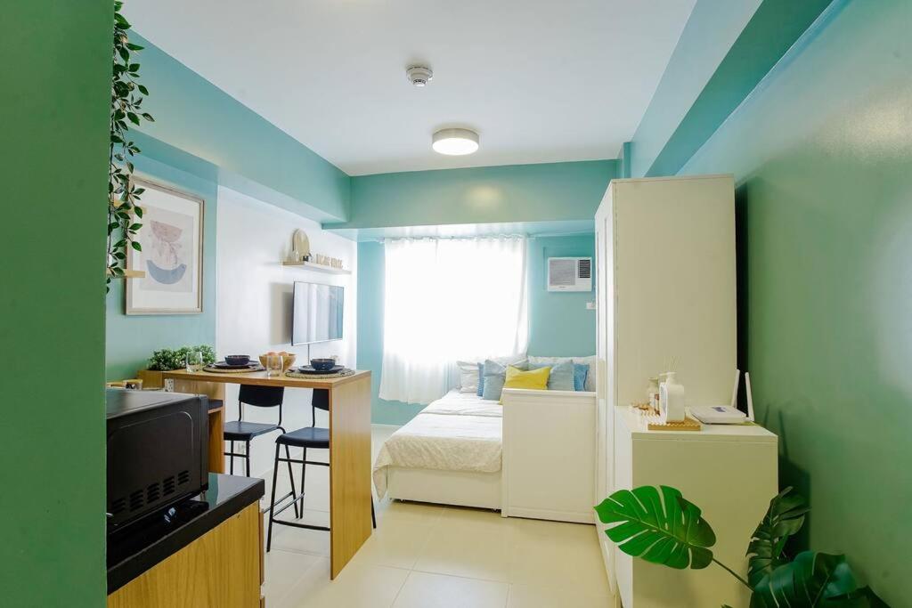 a small room with a bed and a desk and a kitchen at Vicar Home by Serin East Tagaytay in Tagaytay