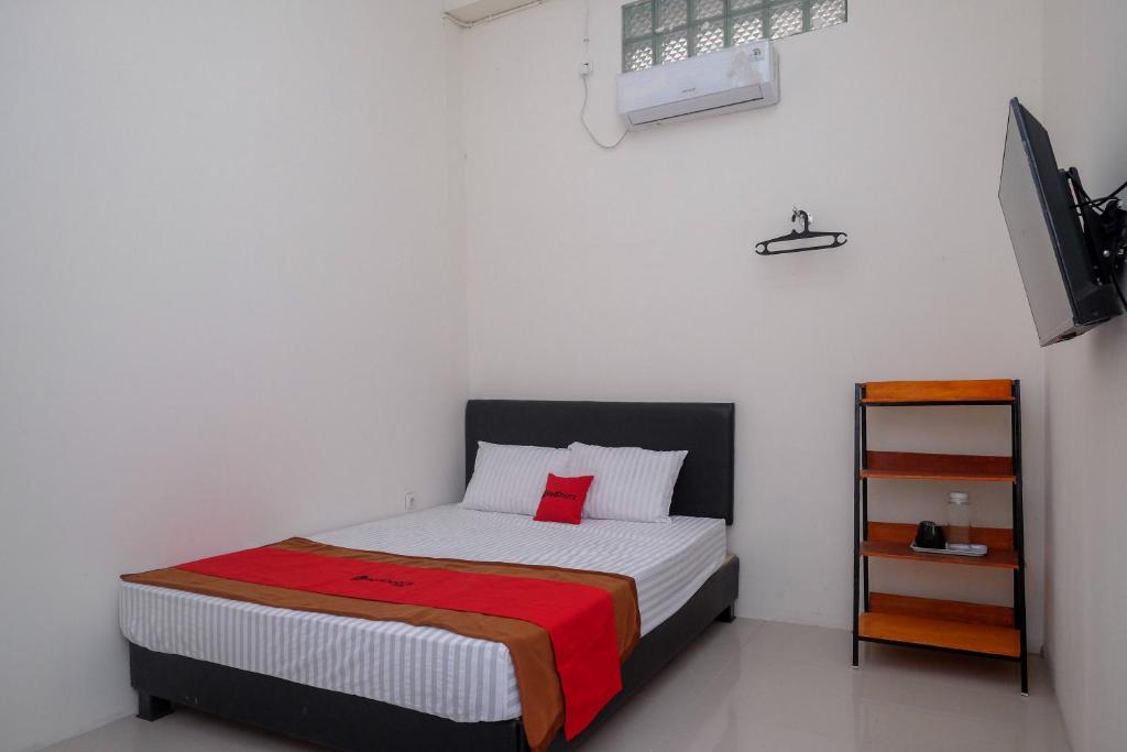 a small bedroom with a bed with a red pillow at RedDoorz near Alun Alun Magelang 2 in Magelang