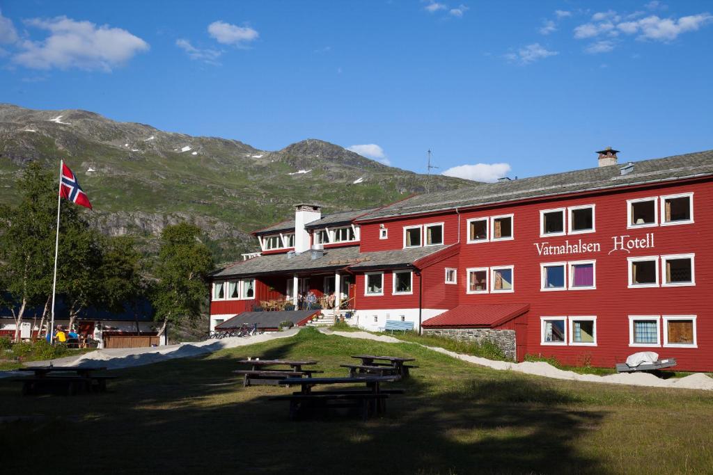 un edificio rojo con mesas de picnic delante de él en Vatnahalsen Høyfjellshotell, en Myrdal