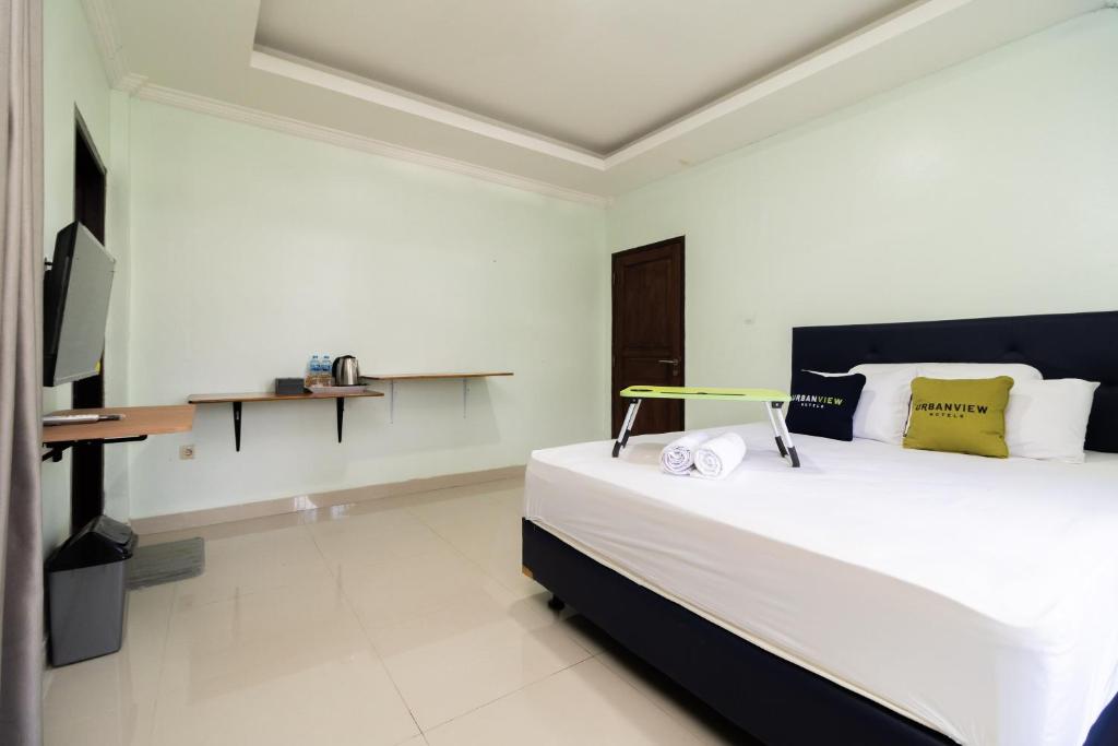 a bedroom with a large bed and a desk at Urbanview Hotel Kampung Istal Megamendung Puncak by RedDoorz in Cipayung