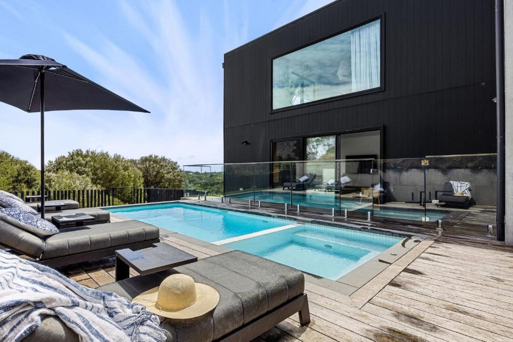 a black house with a swimming pool in front of it at Peninsula Hot Springs Designer Home in Fingal