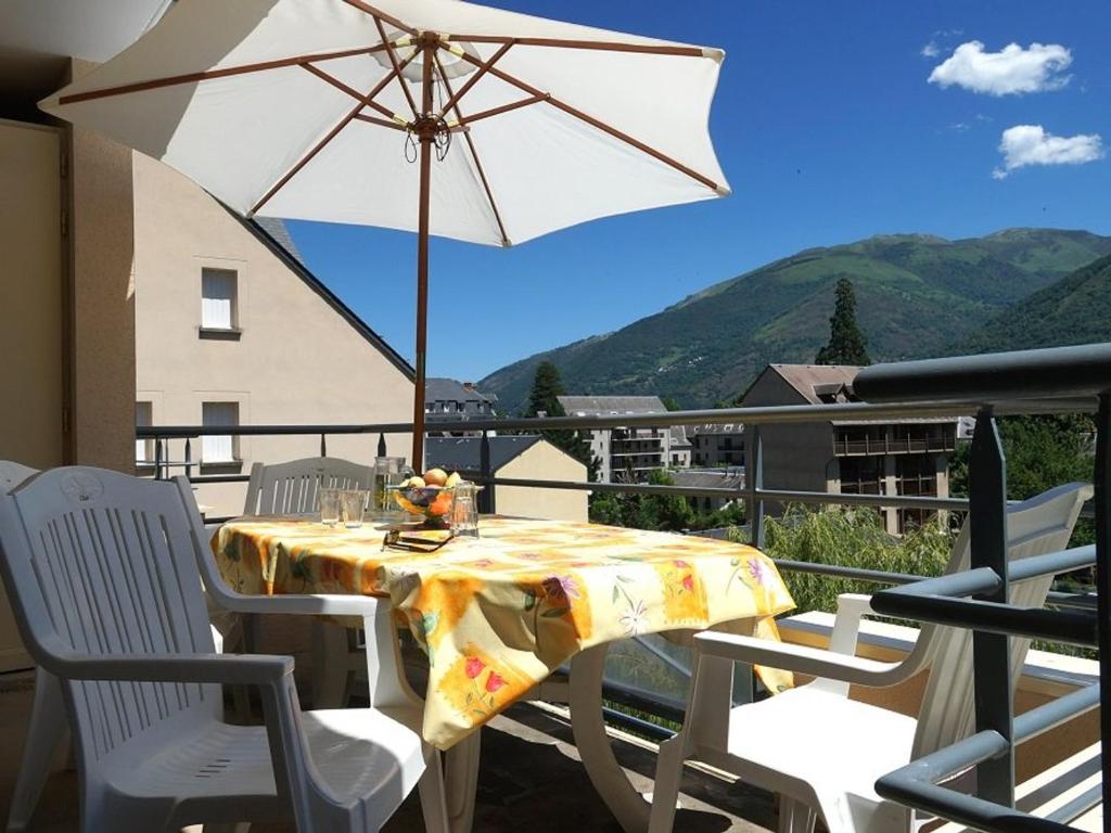 une table et des chaises avec un parasol sur un balcon dans l'établissement LUCHON Appart 2 pièces 4 pers avec balcon et parking, près centre-ville et thermes - FR-1-313-127, à Luchon