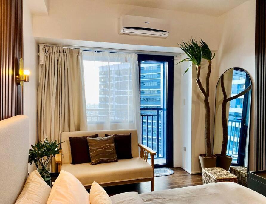 马尼拉Muji-Inspired hōme-tél in the heart of Makati的带沙发和大窗户的客厅