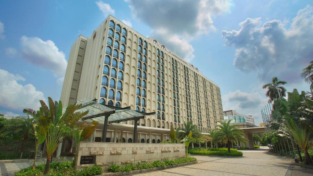 un grand bâtiment avec des palmiers devant lui dans l'établissement InterContinental Dhaka, an IHG Hotel, à Dhaka