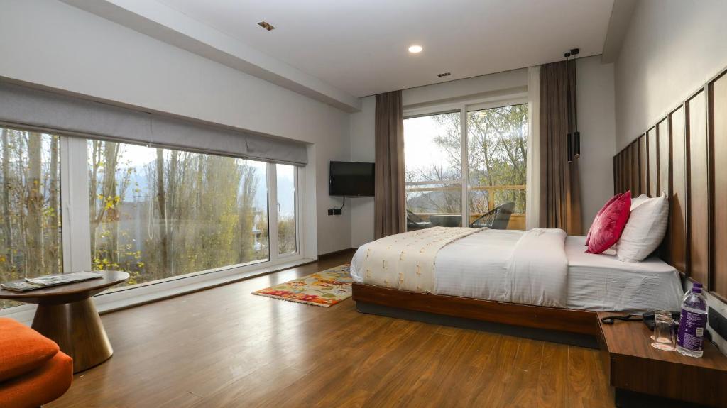 a bedroom with a bed and a large window at Hotel The Kaal in Leh