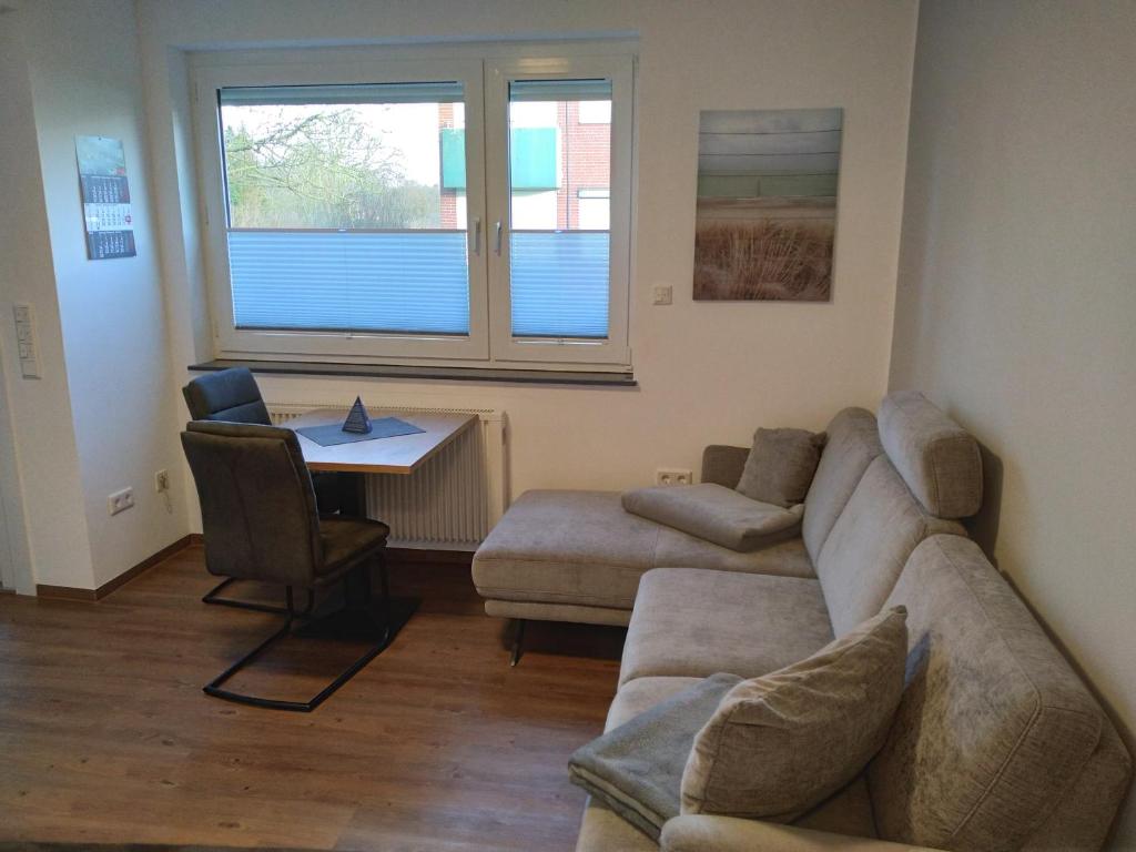 ein Wohnzimmer mit einem Sofa und einem Tisch in der Unterkunft FeWo Kleine Freiheit mit Balkon - Horumersiel in Horumersiel