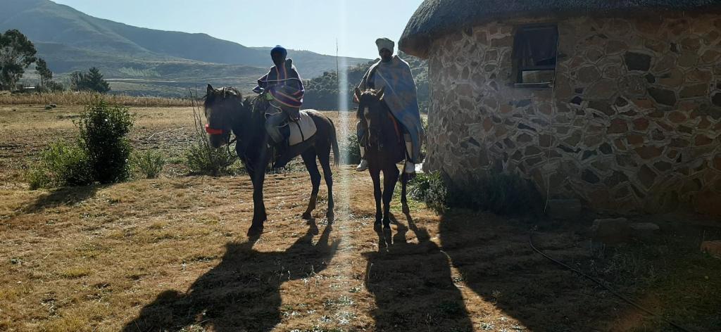 two people riding horses on a dirt road next to a building at Casa Tumi Round Houses. 
