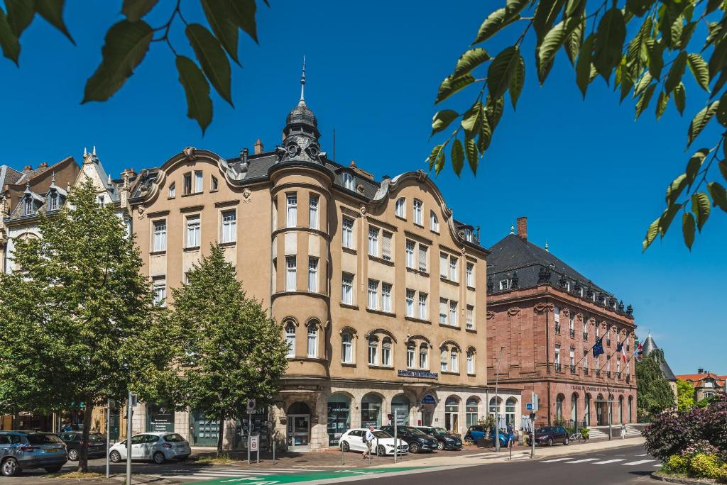 een groot gebouw in een straat met auto's aan de voorkant bij Hôtel Le Mondon Metz in Metz