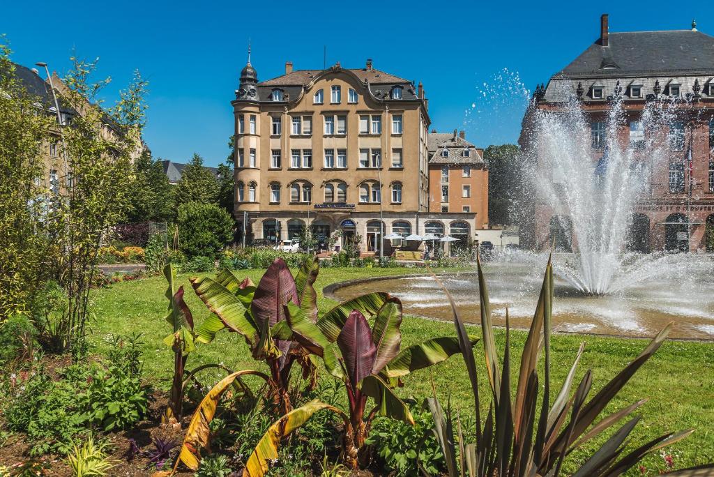 une fontaine en face d'un grand bâtiment dans l'établissement Hôtel Le Mondon, à Metz