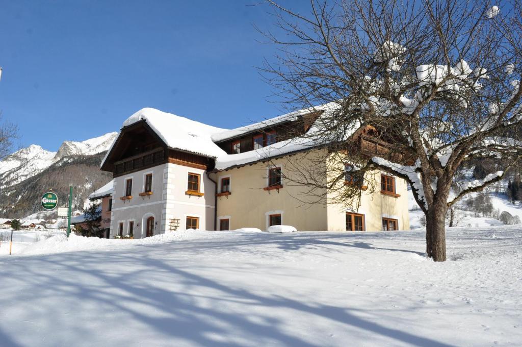 a snow covered building with a tree in front of it at Landhotel Lacknerhof in Mariapfarr