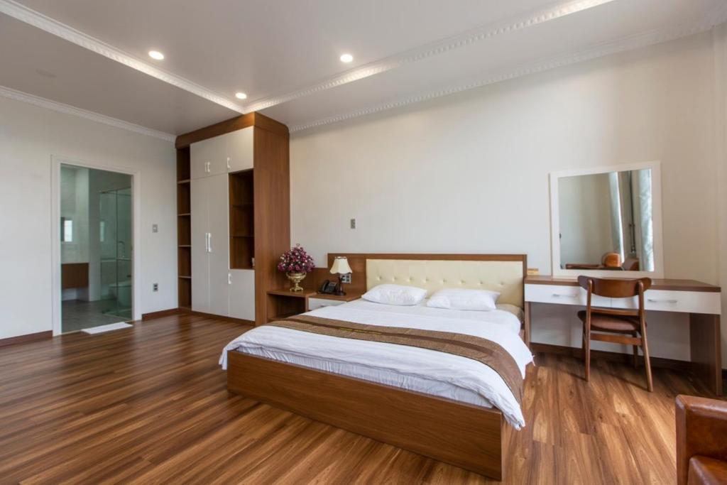 een slaapkamer met een groot bed en een bureau bij Hoang Hung Hotel in Dĩ An