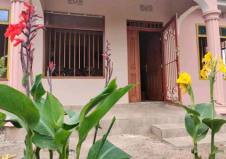 a house with a door and some flowers in front of it at ZIMBE HOST Apartment in Arusha