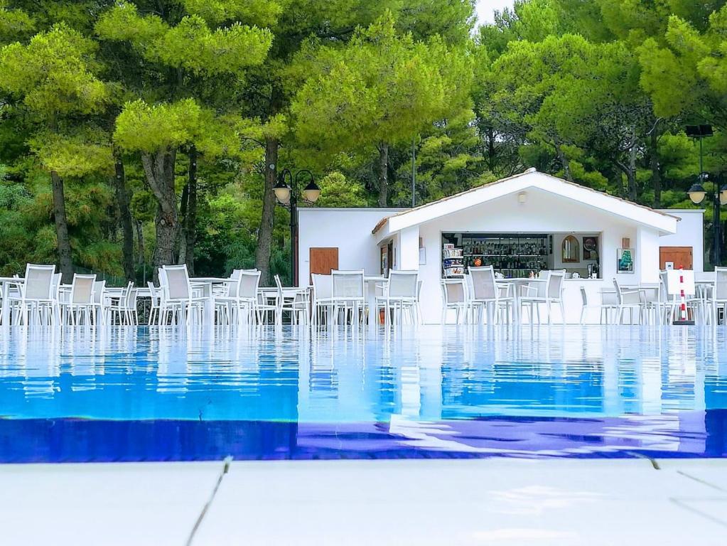 une piscine d'eau avec des chaises blanches et un bâtiment dans l'établissement Hotel Portonuovo, à Vieste