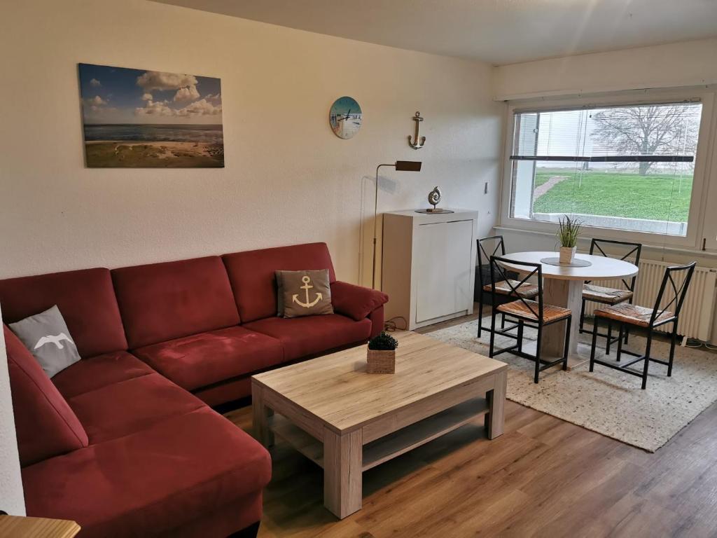 uma sala de estar com um sofá vermelho e uma mesa em FeWo Meerblick - Schillig em Schillig