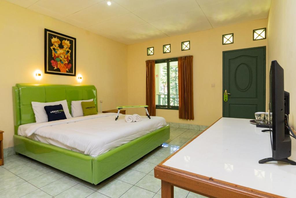 Schlafzimmer mit einem grünen Bett und einem TV in der Unterkunft Urbanview Hotel Griya Astoeti 2 Cisarua Puncak in Kopo 2