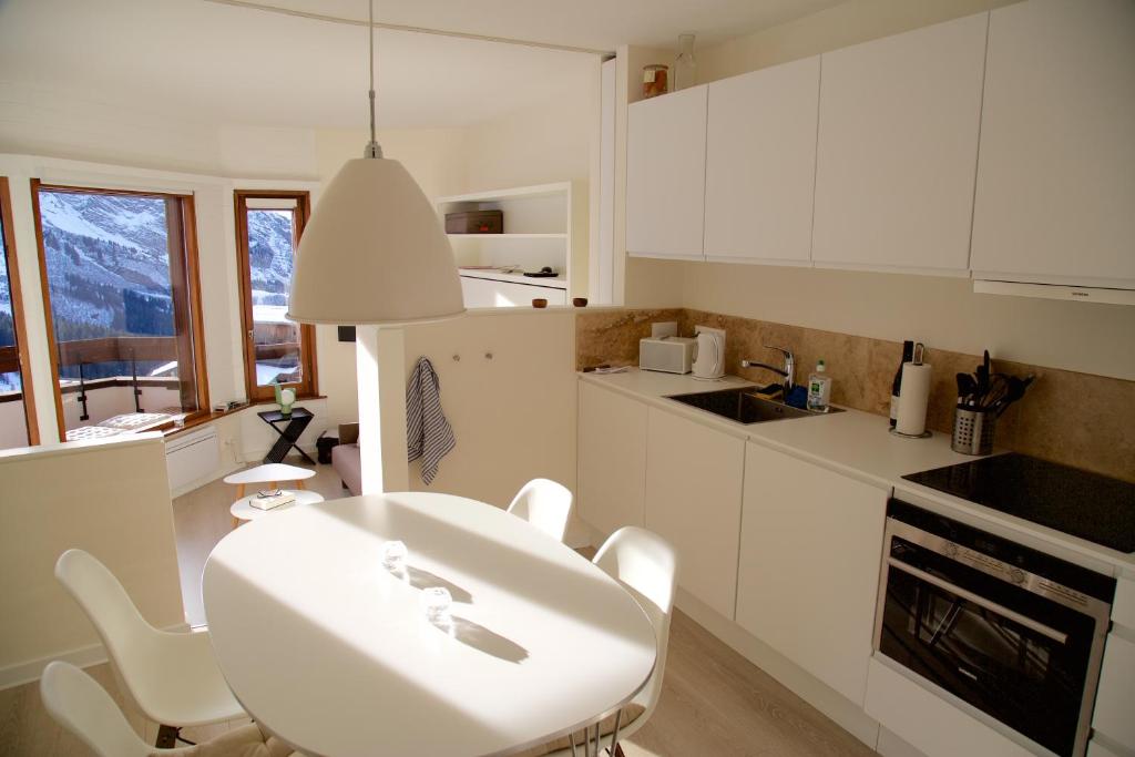 アヴォリアーズにあるMunk - Avoriazの白いキャビネット、テーブルと椅子付きのキッチンが備わります。