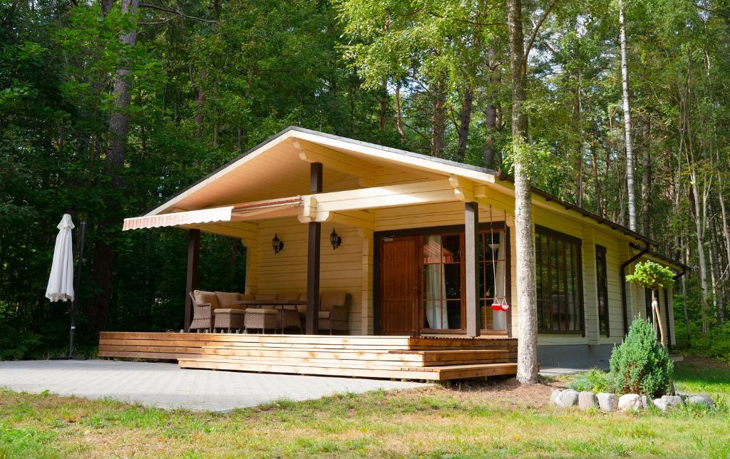 a small yellow cabin with a porch in the woods at Ruhnu Holiday House in Ruhnu