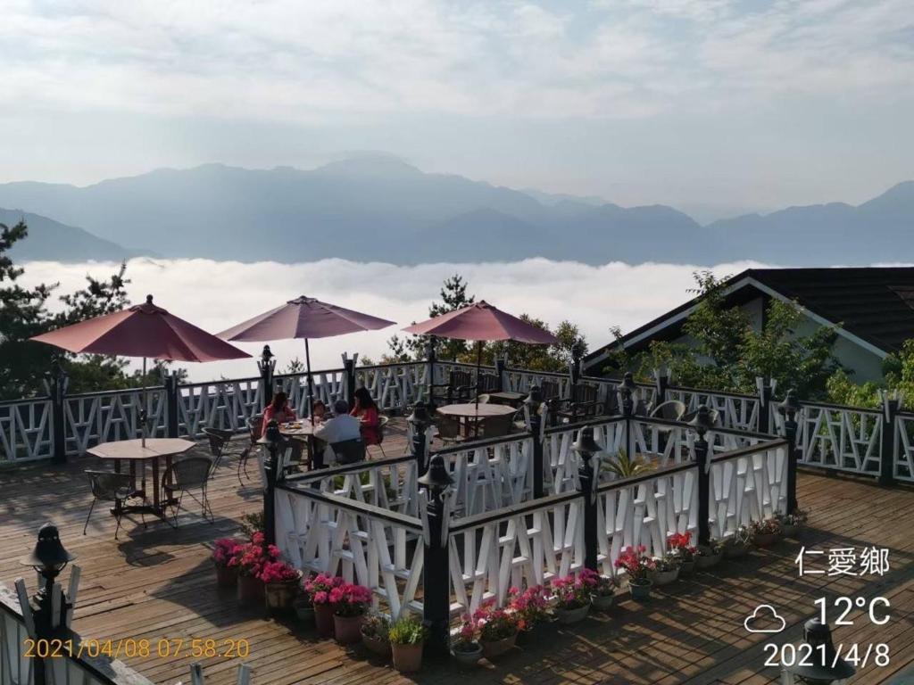 a patio with tables and umbrellas with mountains in the background at Naluwan Villa in Ren&#39;ai