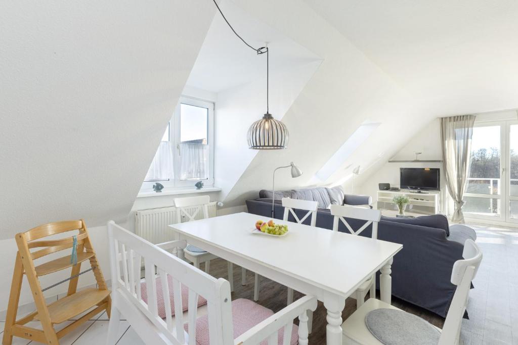cocina y sala de estar con mesa blanca y sillas en Ferienwohnung Die 25 en Timmendorfer Strand