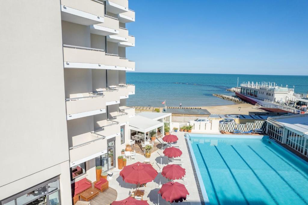 Blick auf den Pool und den Strand von einem Gebäude in der Unterkunft UNAHOTELS Imperial Sport Hotel in Pesaro
