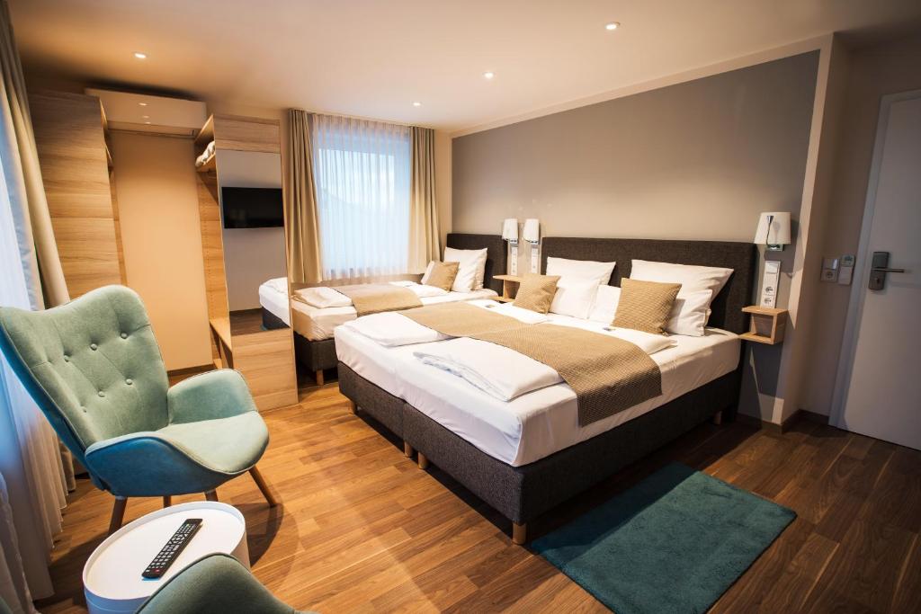 Pokój hotelowy z 2 łóżkami i krzesłem w obiekcie Hotel & Restaurant Rizzelli Superior w mieście Neustadt an der Aisch