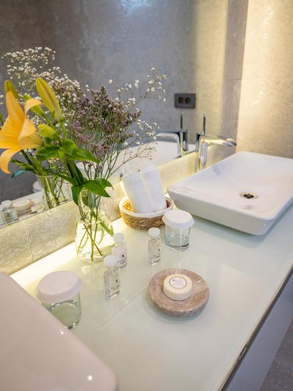 a bathroom counter with a sink and a vase of flowers at Sa'Rezya Hotel in Çeşme