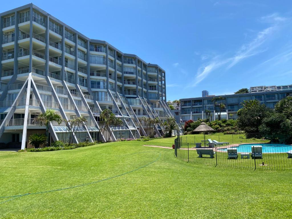 a large building with a lawn in front of it at Kyalanga Beachfront Apartment in Durban