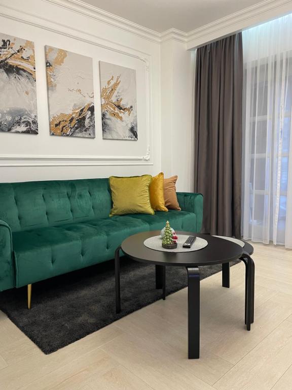 a living room with a green couch and a table at Luxury City Studios in Curtea de Argeş