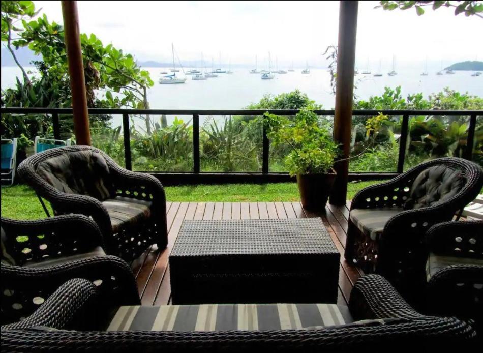 porche con sillas, mesa y vistas al agua en Jurerê Beira Mar Residence, en Florianópolis