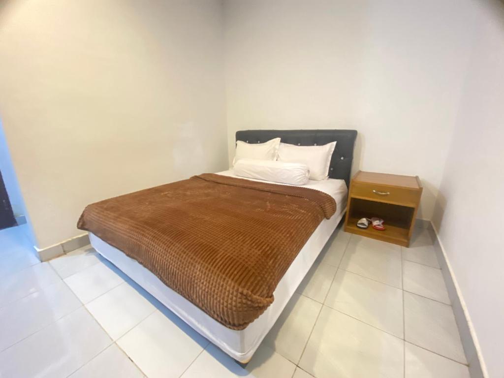 łóżko z brązowym kocem i stolikiem nocnym w obiekcie Villa Matano Sorowako 2 Redpartner w mieście Saroako