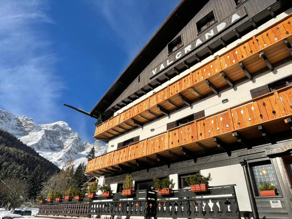 a building with a balcony with mountains in the background at Hotel Valgranda Wellness & Spa in Val di Zoldo
