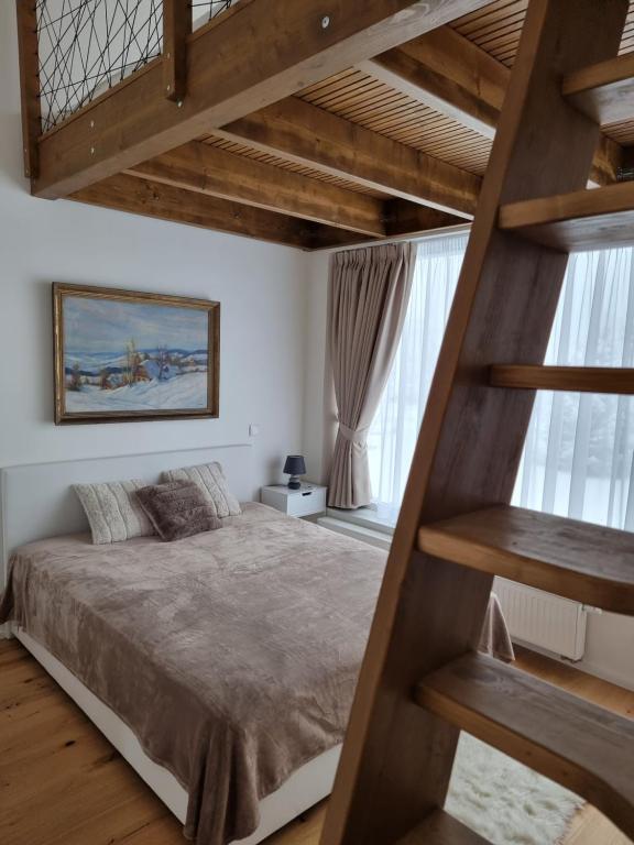 1 dormitorio con cama elevada y escalera en Apartment Max en Loučná pod Klínovcem