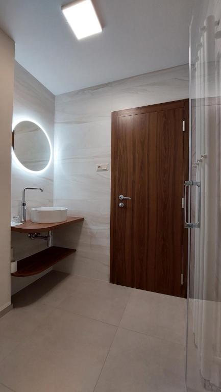 Łazienka z umywalką i drewnianymi drzwiami w obiekcie LONDON Boutique hotel & Restaurant w mieście Trnava