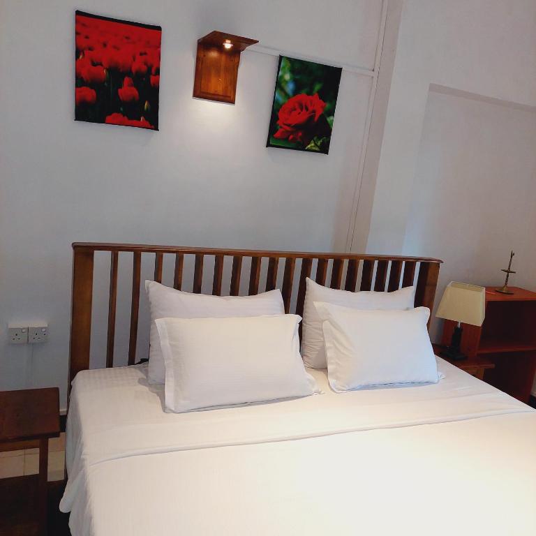 a bedroom with a bed with white sheets and pillows at Golden Villa Kandy in Kandy