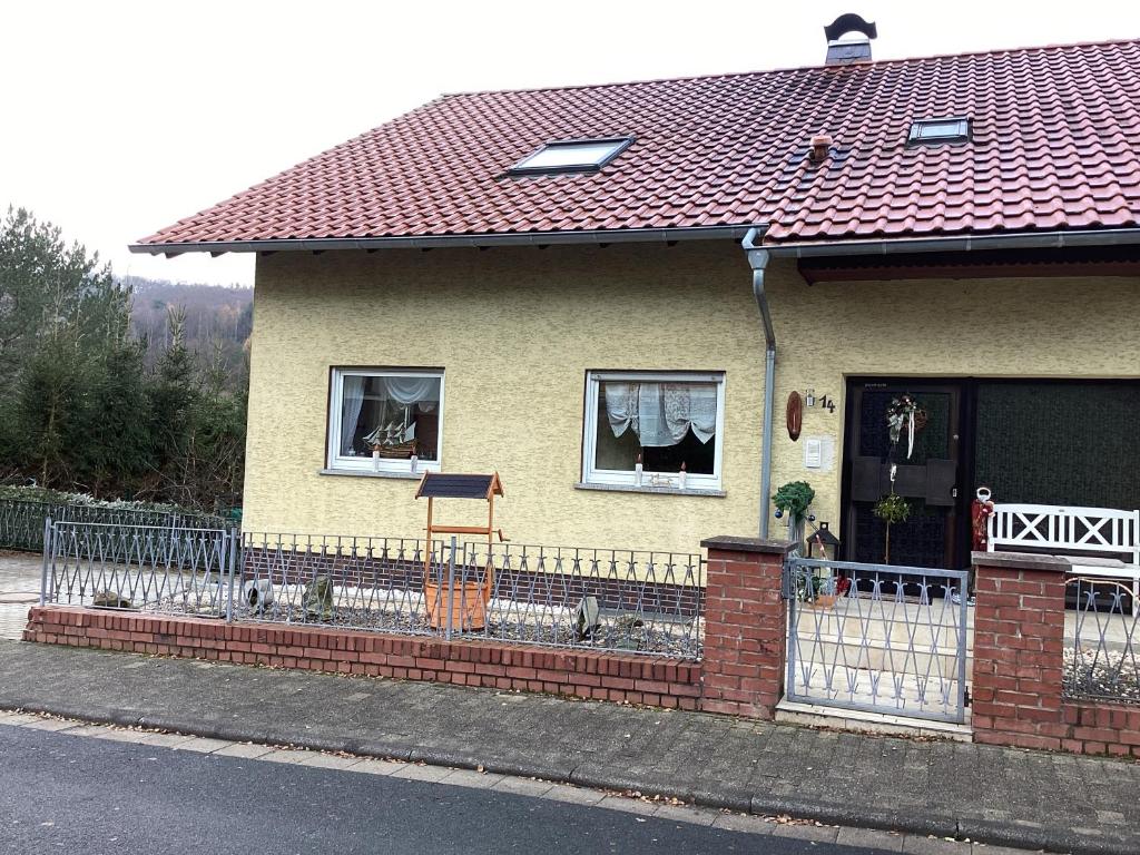 una casa amarilla con una valla delante de ella en Ferienwohnung Keßler, en Waldsolms