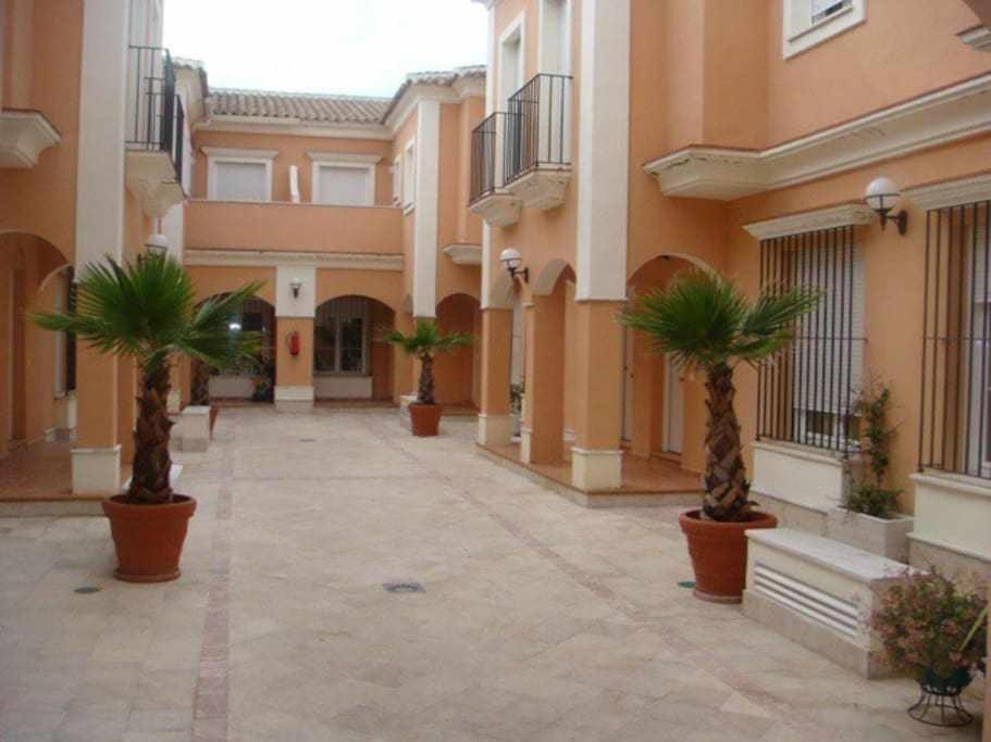 a courtyard with two palm trees in a building at Casa La Rocina Almonte in Almonte
