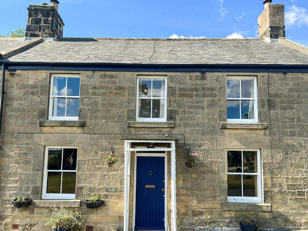 a brick house with a blue door and windows at Blue House Cottage in Elsdon