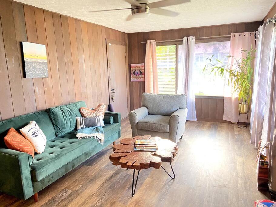 a living room with a green couch and a table at THE HILO HOMEBASE - Charming 3 Bedroom Hilo Home, with AC! in Hilo