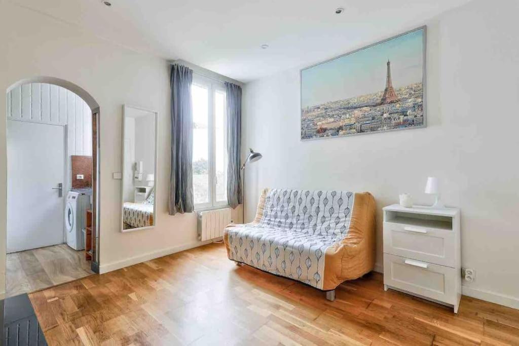 ein Wohnzimmer mit einem Bett, einem Tisch und einem Fenster in der Unterkunft Lumineux & calme Studio à ivry sur seine in Ivry-sur-Seine