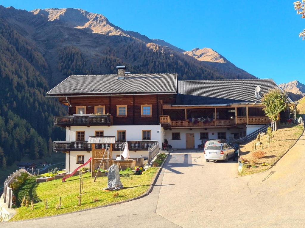 una casa grande en las montañas con un coche aparcado delante en Ausserwalderhof, en Innervillgraten