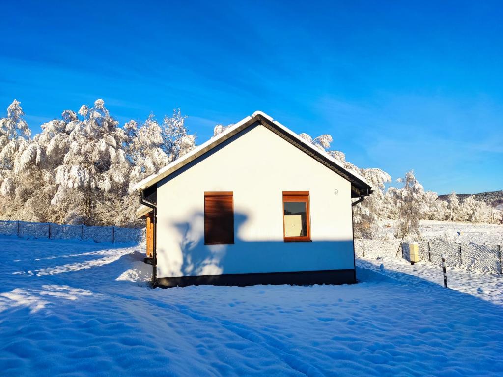 una piccola casa bianca nella neve con gli alberi di Na Stoku Żukowa a Ustrzyki Dolne