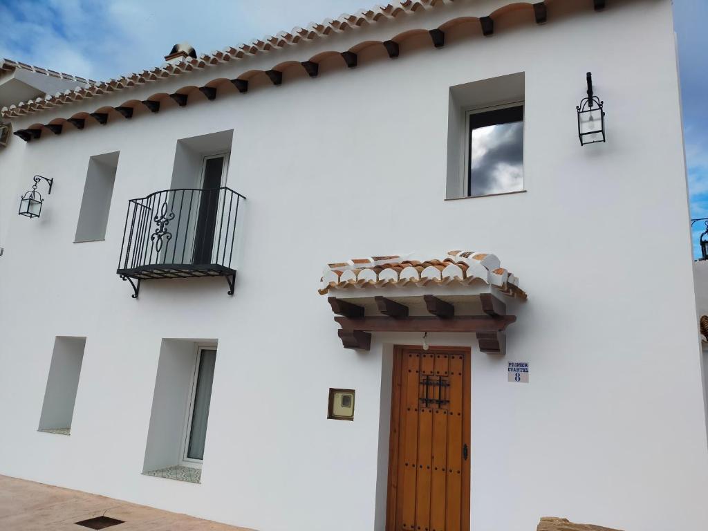 um edifício branco com uma porta de madeira e uma varanda em LA CASA DE LA HUERTA Stylish family cottage in Malaga countryside em Málaga