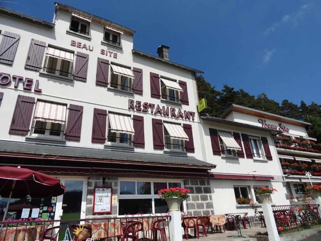 a large white building with a restaurant sign on it at Logis Hôtel Le Beau Site in Chambon-sur-Lac