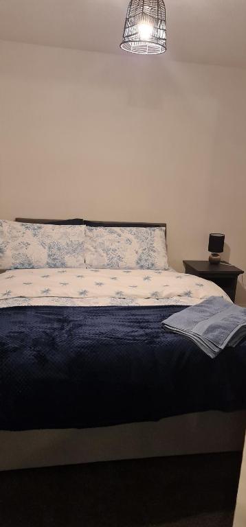 a bedroom with a bed with a blue blanket and a lamp at 3 Bedroom Home - Nerby City Centre in Nottingham