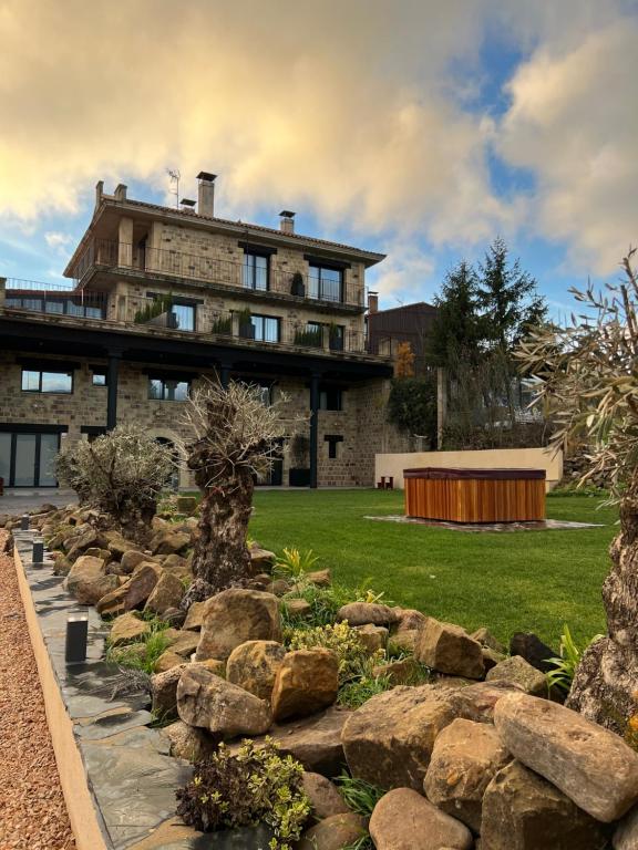 una gran casa de piedra con un jardín delante de ella en Duruelo Mountain Suites, en Duruelo de la Sierra