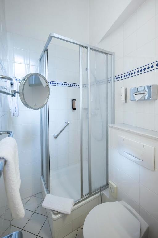 a white bathroom with a shower and a toilet at ACHAT Sternhotel Bonn in Bonn