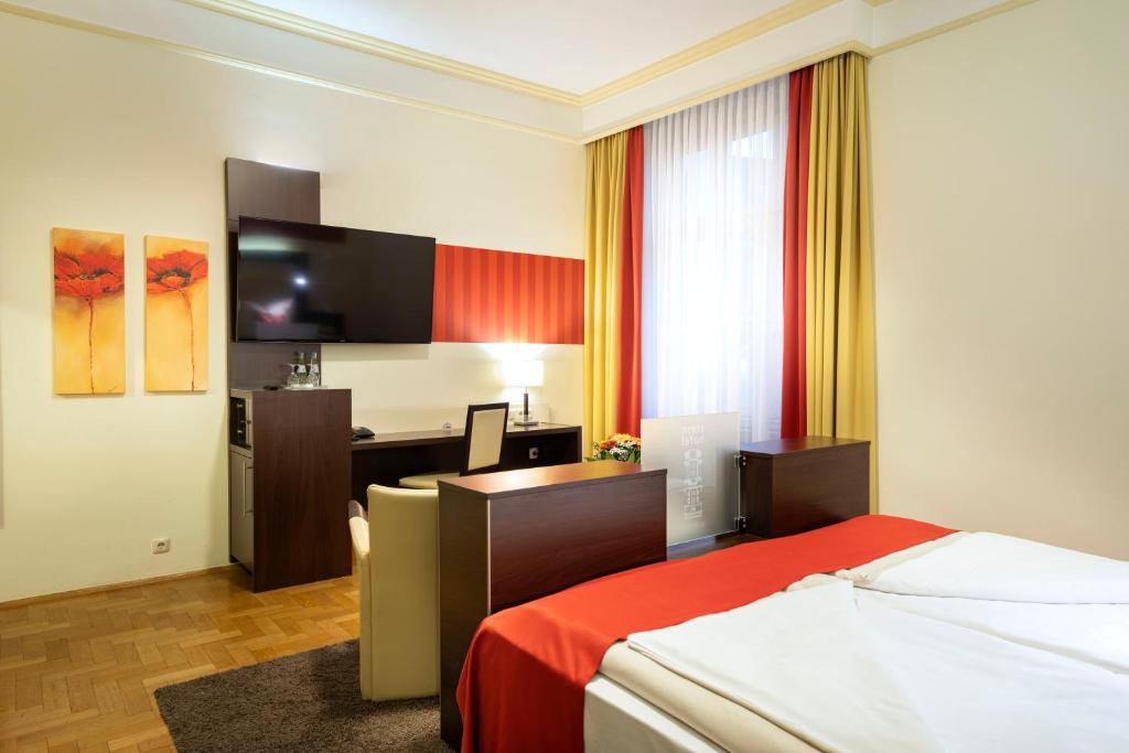 a hotel room with a bed and a desk at ACHAT Sternhotel Bonn in Bonn
