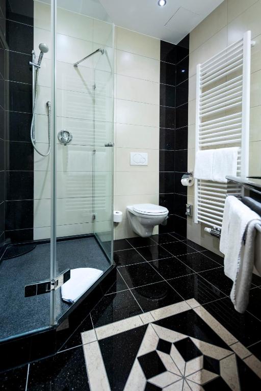a bathroom with a glass shower and a toilet at ACHAT Sternhotel Bonn in Bonn