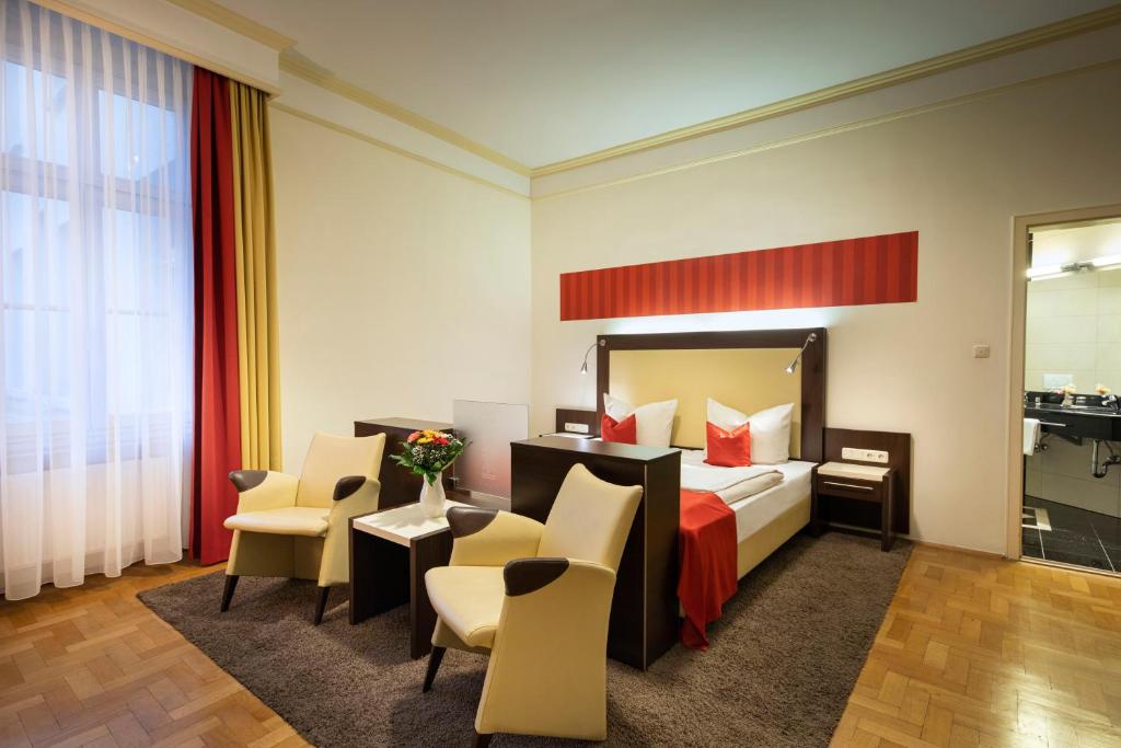 a hotel room with a bed and chairs at ACHAT Sternhotel Bonn in Bonn