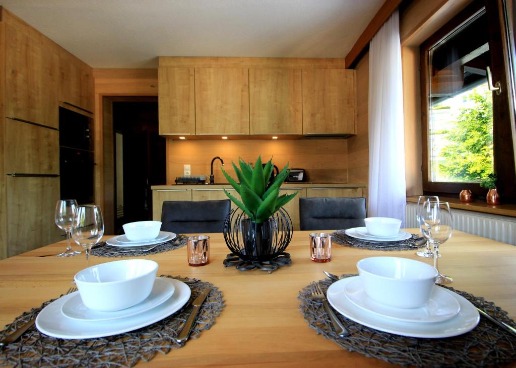 una mesa de madera con platos y copas de vino. en Zell am See Lake View Apartment en Zell am See